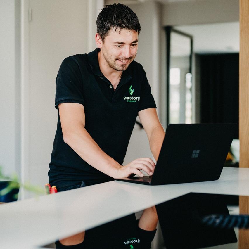 Monteur van Waasdorp werkt op laptop tijdens installatie of controle in moderne woning.