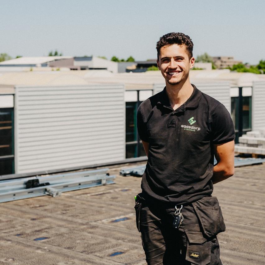 Monteur van Waasdorp op dak bij bedrijfspand tijdens installatie of onderhoudswerkzaamheden.