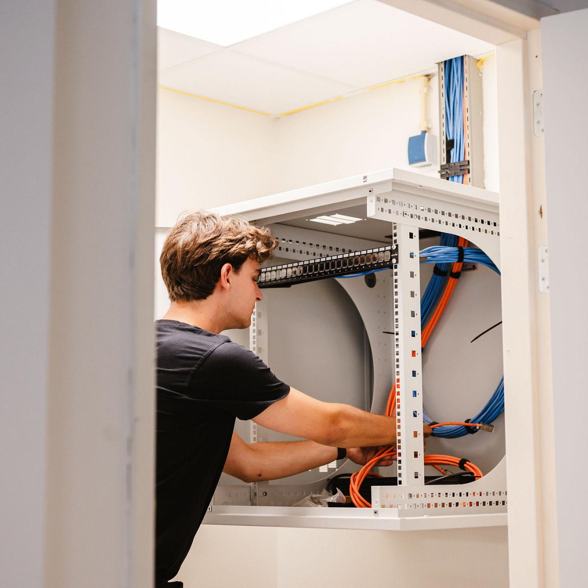 Installateur werkt aan elektrotechnische kast met bekabeling in bedrijfsomgeving