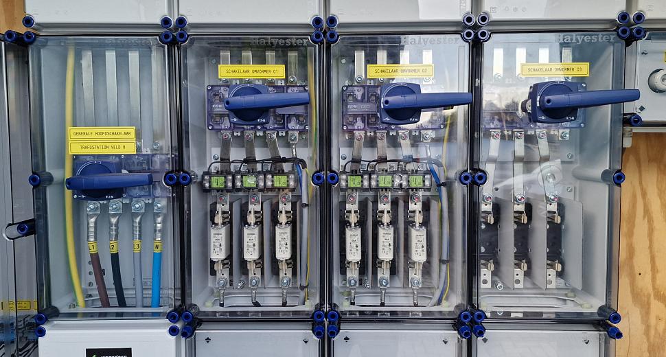 Elektriciteitskast met meerdere doorzichtige panelen, bedrading en schakelaars, gemonteerd tegen een houten achtergrond voor energiebeheer en distributie.